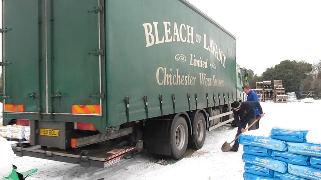 An HGV stuck in the snow with two men attempting to dig it out